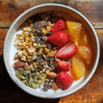 Homemade iron rich cereal bowl topped with strawberries, chia seeds, oats, and pumpkin seeds served with plant-based milk.